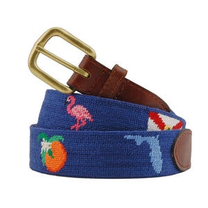 Smathers & Branson’s Florida Life Belt features blue fabric needlepoint with brown Italian leather accents, hand-stitched images of a flamingo, state flag, orange, and whale, and is finished with a brass buckle.