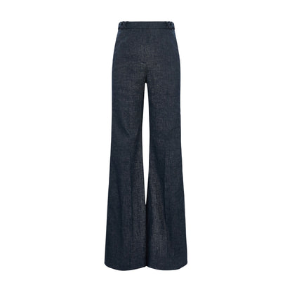 The Fluid Denim Pants by Dorothee Schumacher feature a high-waisted, wide-leg silhouette in dark denim with braided waistband detailing, evoking vintage suiting style, shown against a white background.
