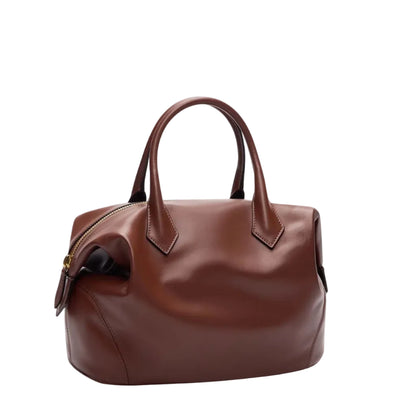 A small TWP Howard Bag, crafted from rich Cognac leather with a structured silhouette, features short handles and a zippered closure, displayed against a white background.