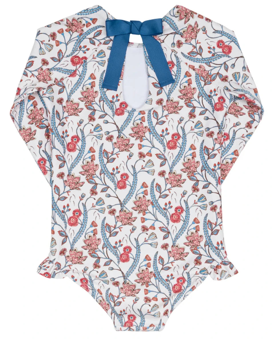 The Minnow Girls' Feathered Floral Rashguard One Piece features long sleeves, a floral pattern, blue bow neckline, and hip ruffles—ideal as stylish swimwear or a sun-safe rashguard for your child.