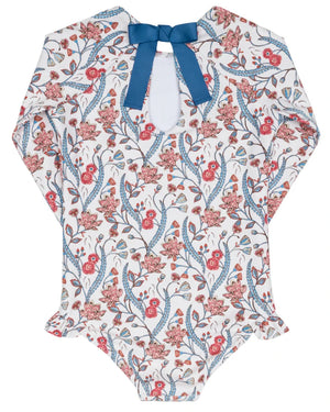 The Minnow Girls' Feathered Floral Rashguard One Piece features long sleeves, a floral pattern, blue bow neckline, and hip ruffles—ideal as stylish swimwear or a sun-safe rashguard for your child.