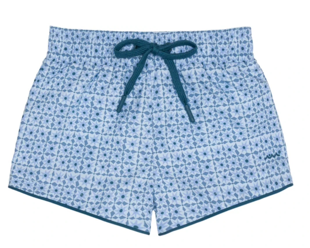 Minnow Boys' Starburst Boardie swim trunks featuring a light blue geometric starburst print, elastic waistband, and dark blue drawstring, laid flat on a white background.