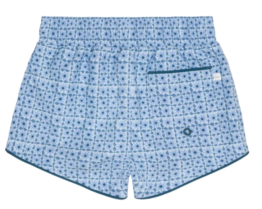 Minnow Boys' Starburst Boardie features a light blue geometric dark blue pattern, single back pocket with teal trim, elastic waistband, and comfy stretch liner.