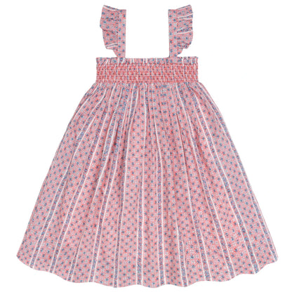 The Minnow Girls' Floral Tile Smocked Dress features a pink and white floral pattern, flutter sleeves, and ruffled shoulder straps, shown against a white background.