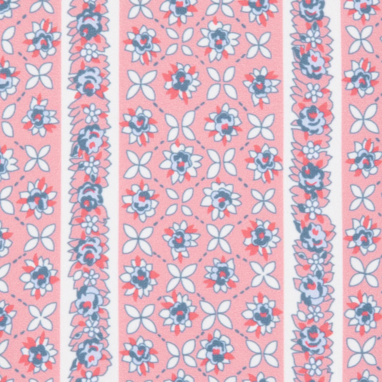 The Minnow Girls' Floral Tile Rashguard One Piece features a floral tile pattern with blue, pink, and white accents on a light pink background—perfect sun-safe swimwear for girls.