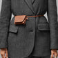 Someone wearing a grey herringbone blazer and trousers accessorized with the Lie Studio Stella Wallet, a small brown Italian cow leather belt bag, fastened around the waist for a versatile look.