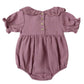 The Quincy Mae Baby Girls' Collared Romper features puff sleeves, a ruffled collar, charming ruffle details, three wooden back buttons, and gathered leg openings.
