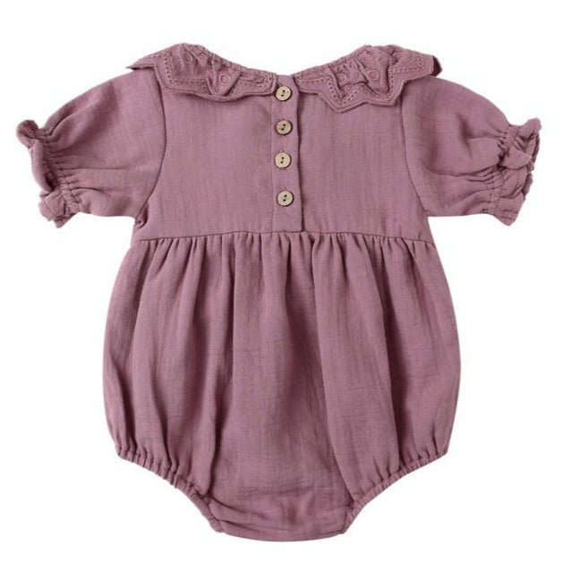 The Quincy Mae Baby Girls' Collared Romper features puff sleeves, a ruffled collar, charming ruffle details, three wooden back buttons, and gathered leg openings.