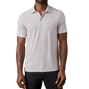 A man wearing the Faherty Movement Polo in light gray and white stripes paired with dark pants, standing against a white background.