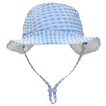 The Snapper Rock Seaside Gingham Reversible Bucket Hat features a light blue and white checkered design, UPF50+ sun protection, a chin strap, and adjustable toggle—perfect for kids on sunny days. Displayed on a white background.