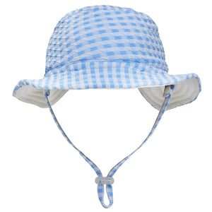 The Snapper Rock Seaside Gingham Reversible Bucket Hat features a light blue and white checkered design, UPF50+ sun protection, a chin strap, and adjustable toggle—perfect for kids on sunny days. Displayed on a white background.