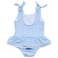 The Snapper Rock Baby Girls' Seaside Gingham Skirt Swimsuit features blue and white gingham, shoulder tie straps, a ruffled detail, and UPF50+ sun protection for stylish safety at the beach.
