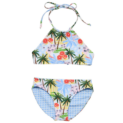 The Snapper Rock Girls' Ciao Paradiso Reversible Halter Bikini features an Italian-inspired tropical print with palm trees, citrus fruits, and blue leaves. Includes a halter neck top and mid-rise bottoms.
