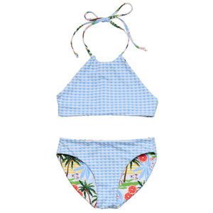 Snapper Rock Girls' Ciao Paradiso Reversible Halter Bikini features a two-piece design with a halter top and matching bottoms, both decorated in colorful tropical fruit and palm tree prints.