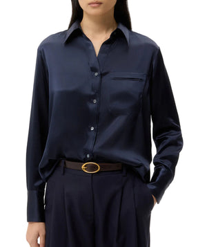 A person wearing the TWP Joey Silk Shirt in dark navy, styled with dark trousers and a black belt featuring a gold buckle.