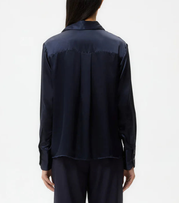 Someone wearing the TWP Joey Silk Shirt, a long-sleeve dark navy classic-fit top, paired with matching pants, shown from the back against a plain white background.