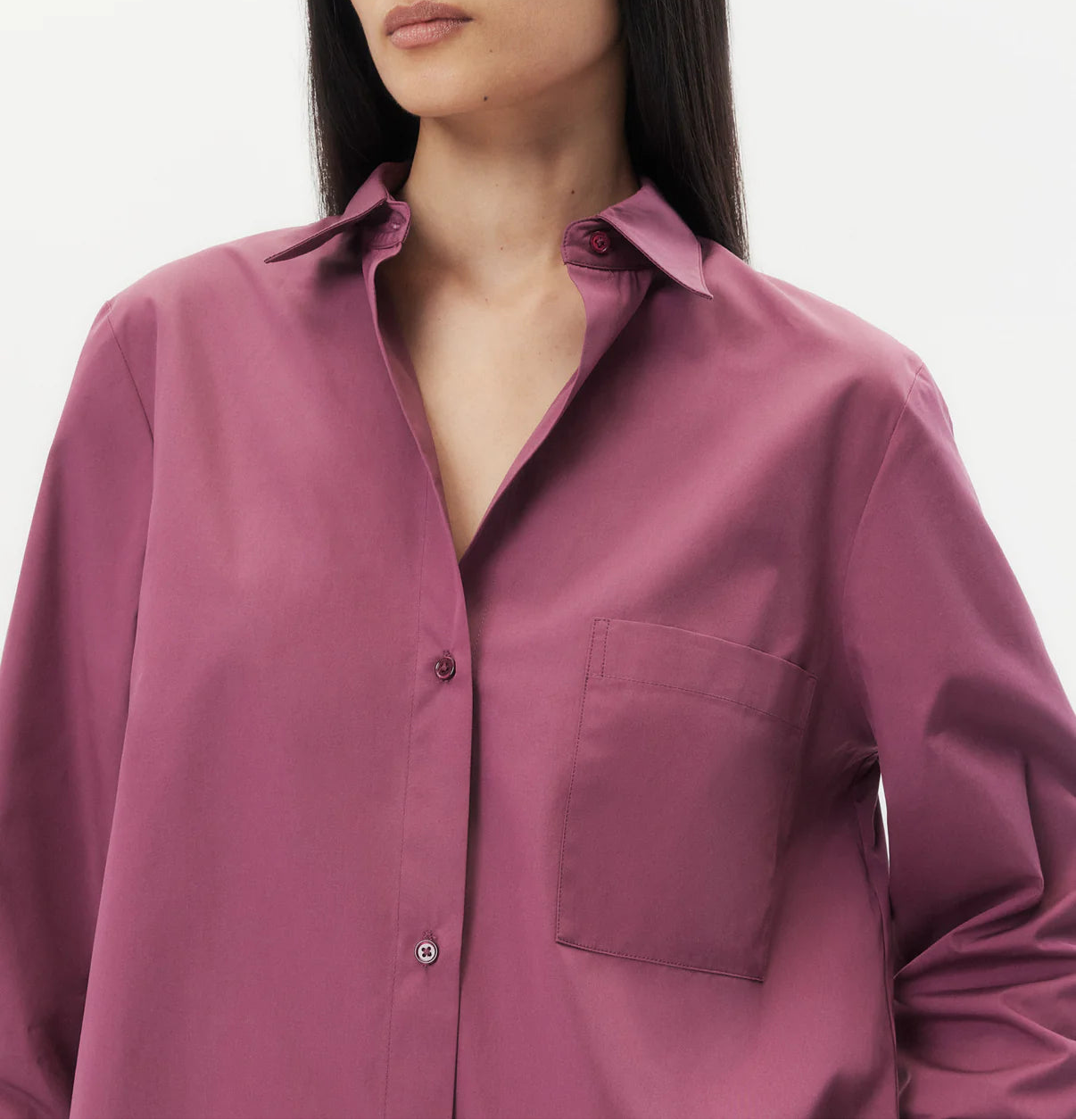 A woman wears the TWP Next Morning Shirt, a magenta oversized button down with a chest pocket and relaxed fit, standing against a plain white background.