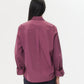 A person with long dark hair is shown from the back, wearing the TWP Next Morning Shirt in magenta with a relaxed, oversized fit, paired with dark pants against a plain white background.