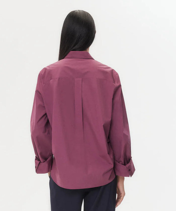 A person with long dark hair is shown from the back, wearing the TWP Next Morning Shirt in magenta with a relaxed, oversized fit, paired with dark pants against a plain white background.