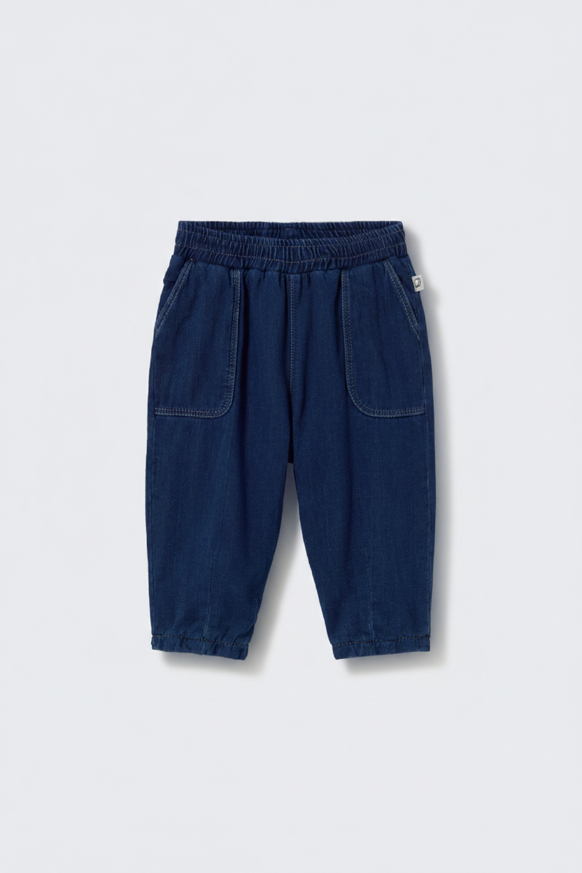 A pair of Cozmo Baby Galo Denim Pants for children, featuring a dark blue herringbone twill, elastic waistband, and two front pockets, displayed against a plain white background.