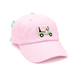 The Dog Golf Cart Bow Hat by Bits & Bows is a light pink baseball cap featuring an embroidered design of a person driving a green golf cart filled with golf clubs. This delightful hat offers playful style and comfortable sun protection, making it the perfect golf accessory for kids.