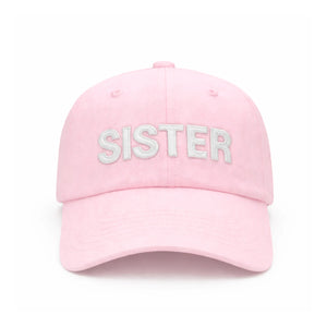 A light pink Sister Bow Hat by Bits & Bows, featuring “SISTER” embroidered in large white letters on the front and an adjustable tuckstrap for a comfortable fit—perfect for celebrating sisterhood in style.