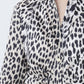 Close-up of a person wearing the Genny Cheetah Shirtdress by Callas Milano, featuring a black and white cheetah print in Italian stretch cotton sateen, layered over a beige top.