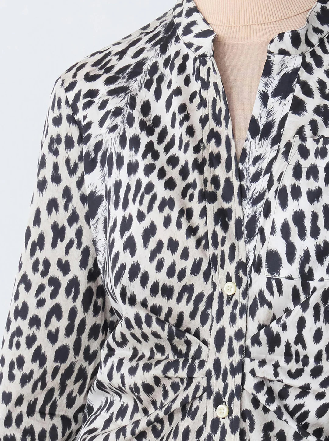 Close-up of a person wearing the Genny Cheetah Shirtdress by Callas Milano, featuring a black and white cheetah print in Italian stretch cotton sateen, layered over a beige top.