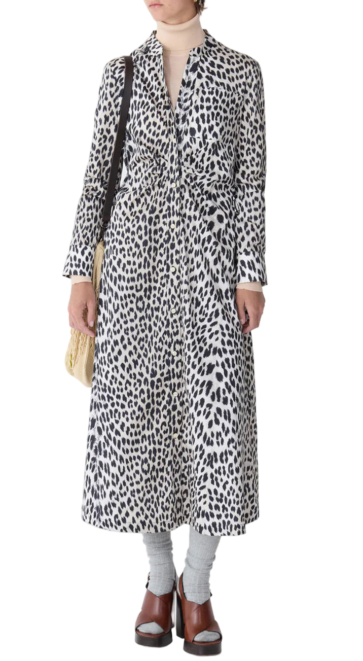 A person wearing the Callas Milano Genny Cheetah Shirtdress styled with a beige turtleneck, gray socks, brown sandals, and a cream shoulder bag.