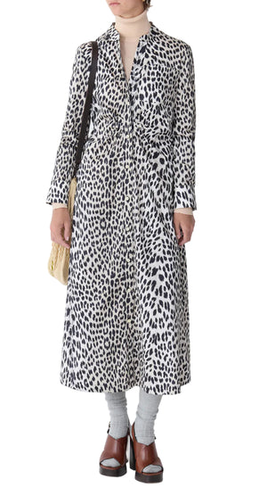 A person wearing the Callas Milano Genny Cheetah Shirtdress styled with a beige turtleneck, gray socks, brown sandals, and a cream shoulder bag.