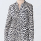 A person wearing the Genny Cheetah Shirtdress by Callas Milano over a beige turtleneck top.