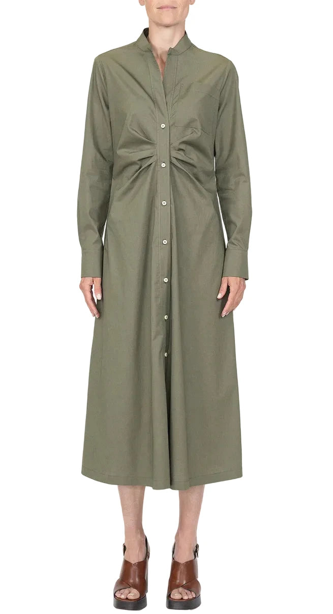 A person wearing the Genny Dress by Callas Milano, a long sleeve button front dress in olive green Italian shirting twill with a gathered waist, paired with brown open-toe sandals.