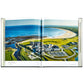 An aerial view of a coastal golf resort with lush greens and a curved shoreline is featured across an open spread in "Golf: The Ultimate Book" by Graphic Image.