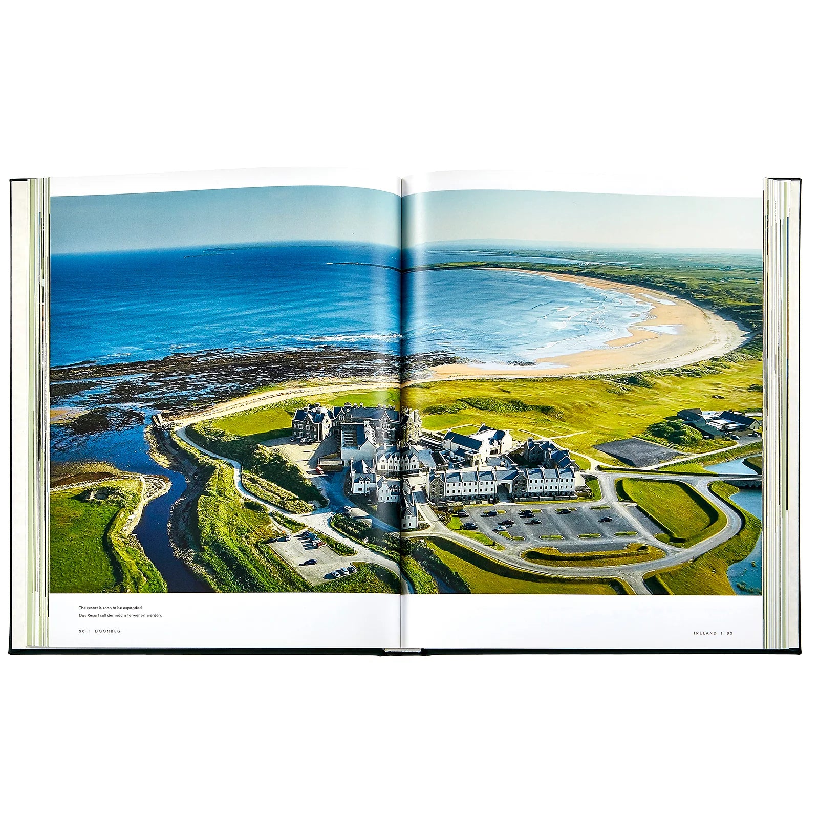 An aerial view of a coastal golf resort with lush greens and a curved shoreline is featured across an open spread in "Golf: The Ultimate Book" by Graphic Image.