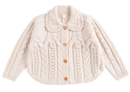 The Girls' Khellana Cape Sweater by Louise Misha is a cream-colored knitted cardigan featuring a delicate Peter Pan collar, cable knit pattern, and wooden buttons down the front.