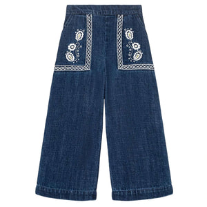 The Girls' Flofi Pants by Louise Misha are wide-leg blue denim pants with white floral embroidery, decorative front pocket stitching, and an elastic waist for comfort.