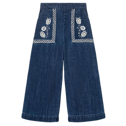 The Girls' Flofi Pants by Louise Misha are wide-leg blue denim pants with white floral embroidery, decorative front pocket stitching, and an elastic waist for comfort.