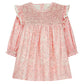 The Girls' Saralou Dress by Louise Misha is a pink cotton gauze long-sleeve dress with a white floral print, smocked chest, ruffled shoulders, and elastic cuffs.