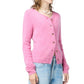 A person wears the Grizzly Cashmere Cardigan by Guest in Residence in fuzzy pink, paired with light blue jeans and layered necklaces, set against a white background.