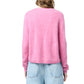 A person wearing the Grizzly Cashmere Cardigan by Guest in Residence and light blue jeans, shown from the back against a white background.