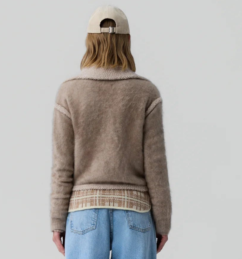 Wearing the Grizzly Frankie Jacket by Guest in Residence, a person in light blue jeans and a beige cap stands with their back to the camera against a plain light background.