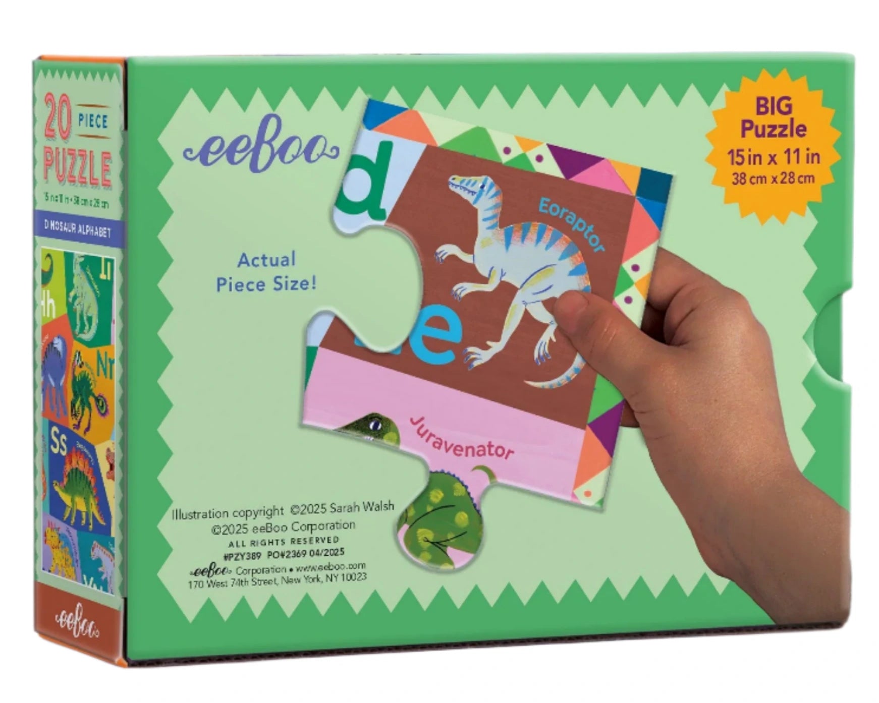 A hand holds a dinosaur puzzle piece in front of a green Eeboo Dinosaur Alphabet 20 Piece Puzzle box, which features colorful artwork and shows the puzzle’s size for children learning.