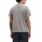 A person is shown from the back wearing a Rag & Bone Garment Dye Classic Pocket Tee and dark jeans, with several tattoos visible on both arms.