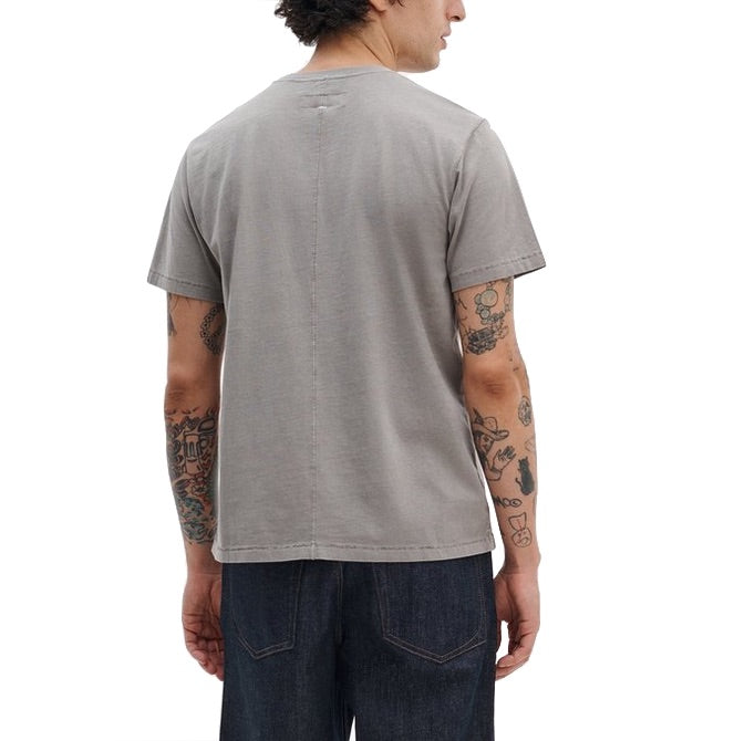 A person is shown from the back wearing a Rag & Bone Garment Dye Classic Pocket Tee and dark jeans, with several tattoos visible on both arms.