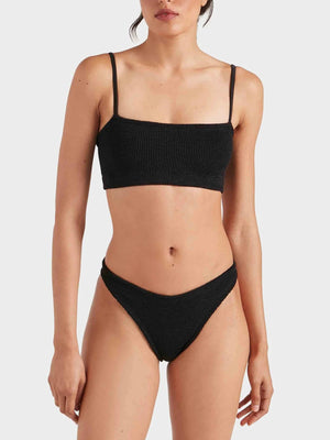 A woman wears the Hunza G Gigi Bikini in black crinkle fabric, featuring a straight neckline top and high-cut bottoms, against a plain light background.
