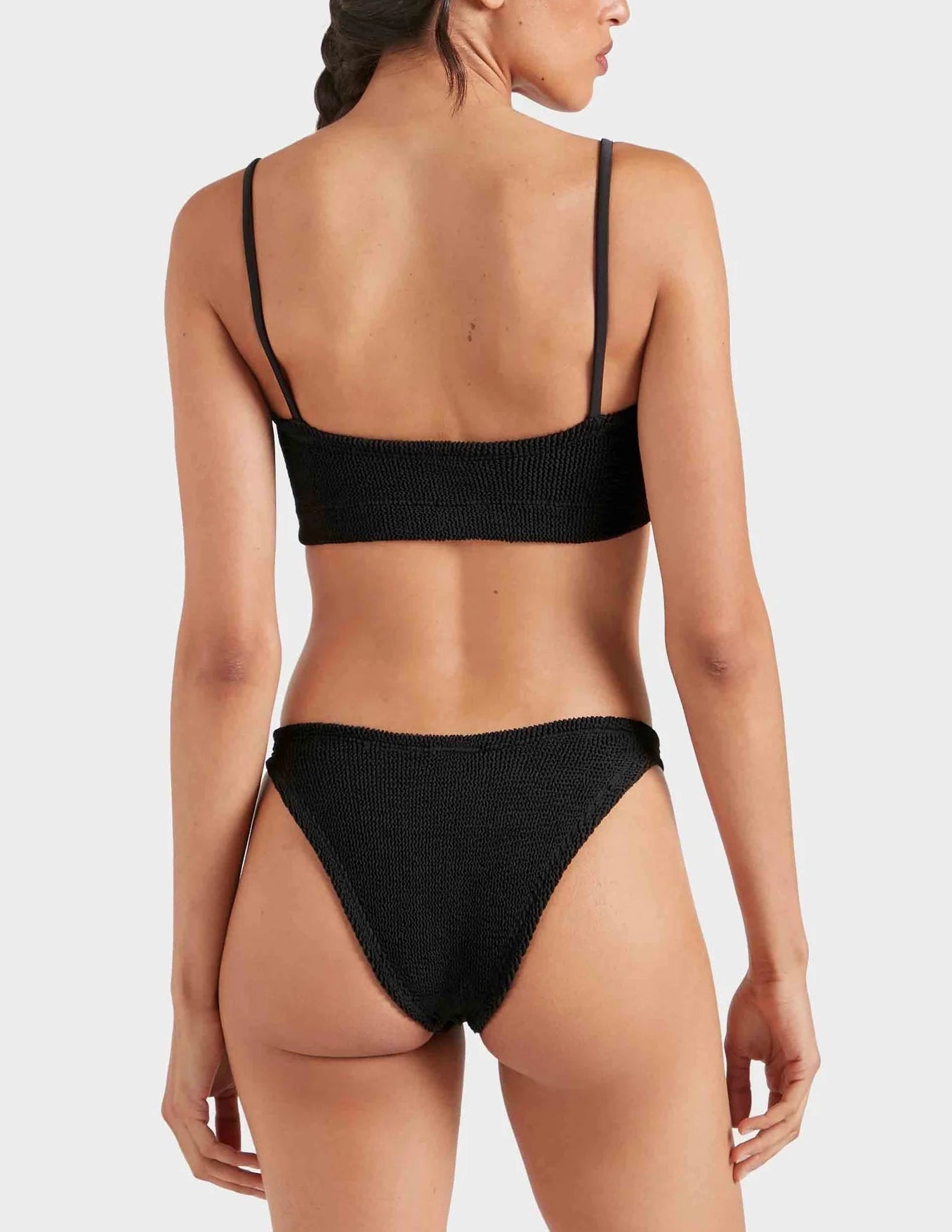 Model wearing the Hunza G Gigi Bikini in black crinkle fabric, shown from the back against a plain light gray background.