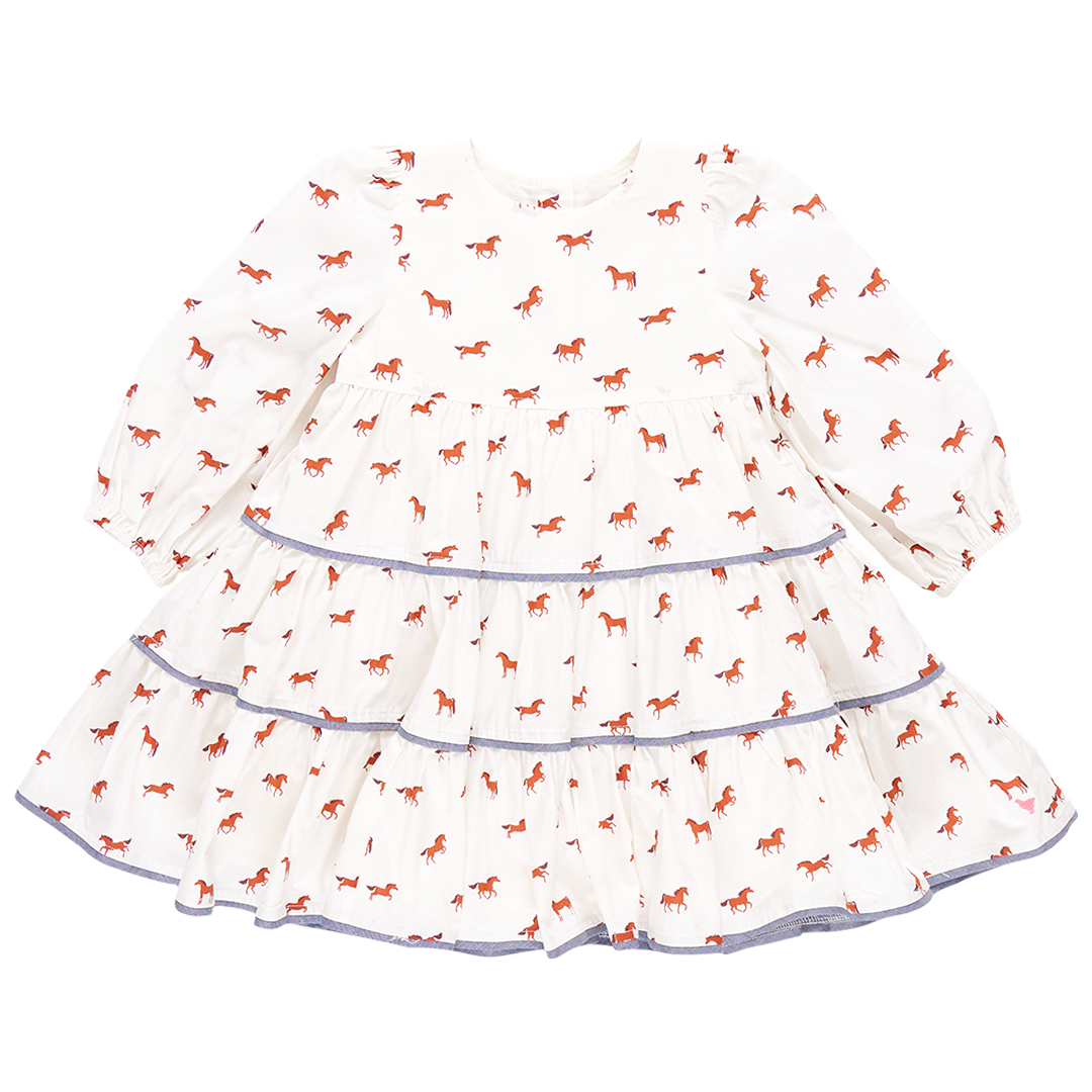 The Pink Chicken Girls' Julia Dress captures equestrian chic with its white long-sleeved design, showcasing chambray detailed tiers and delightful red horse prints on the tiered skirt.