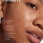 Close-up of a woman's face with a swatch of Supergoop Glowscreen SPF 40 in Golden Hour, highlighting SPF 40 protection, all-day hydration, and benefits for normal, combination, or dry skin.