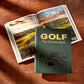 A closed "Golf: The Ultimate Book" by Graphic Image rests on a wooden surface beside an open book showcasing impressive golf courses—an ideal gift for golf lovers.