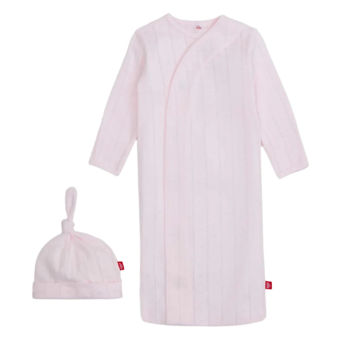 The Magnetic Me Love Lines Gown + Hat Set features a light pink newborn gown with subtle stripes, made from soft organic cotton and equipped with magnetic closures for easy changes. It comes with a matching knotted beanie, all beautifully showcased on a white background.